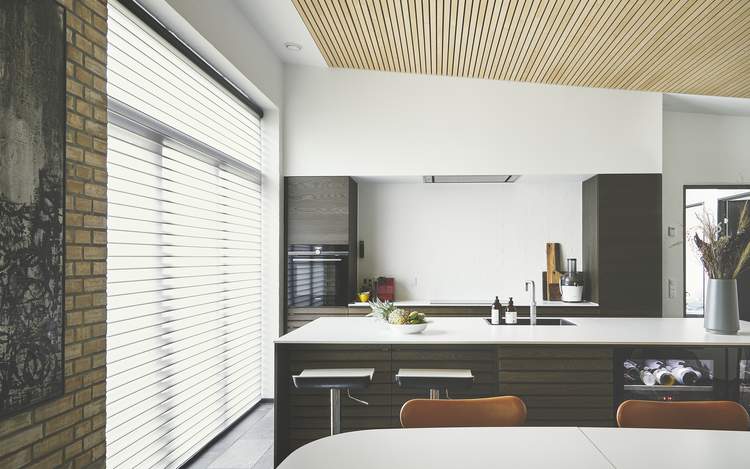 Automatisert Silhouette® gardin i kjøkkenets panoramavinduer hjemme hos Charlotte.