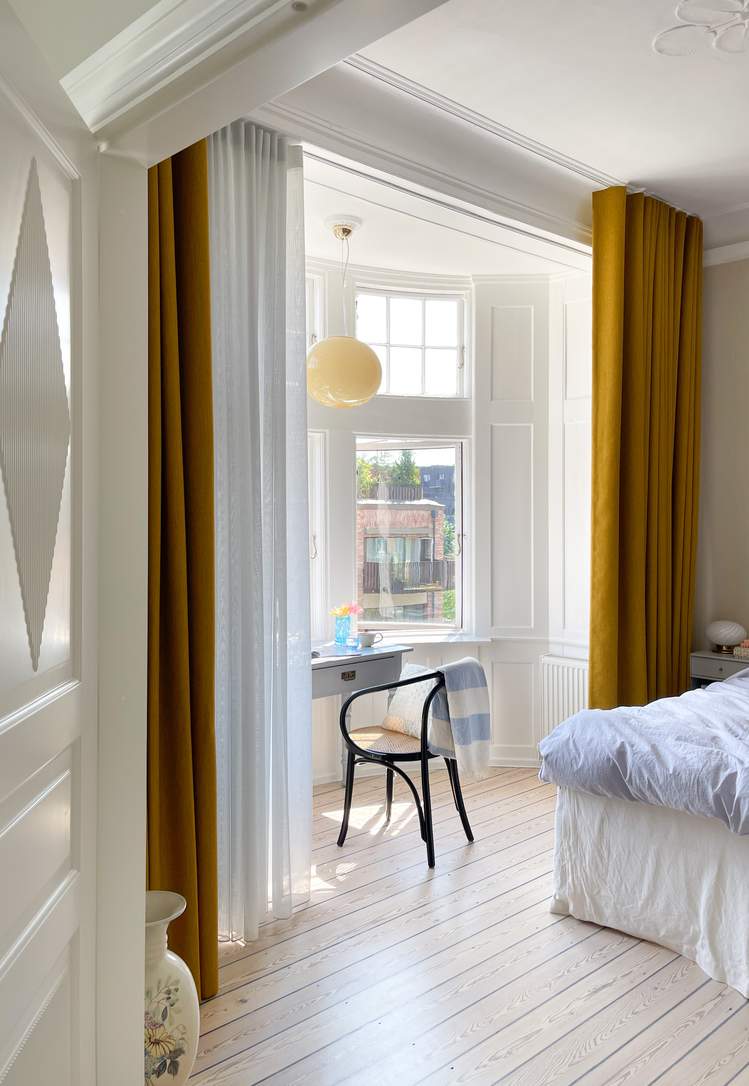 Okergule gardiner i kombinasjon med lyse, flortynne gardiner