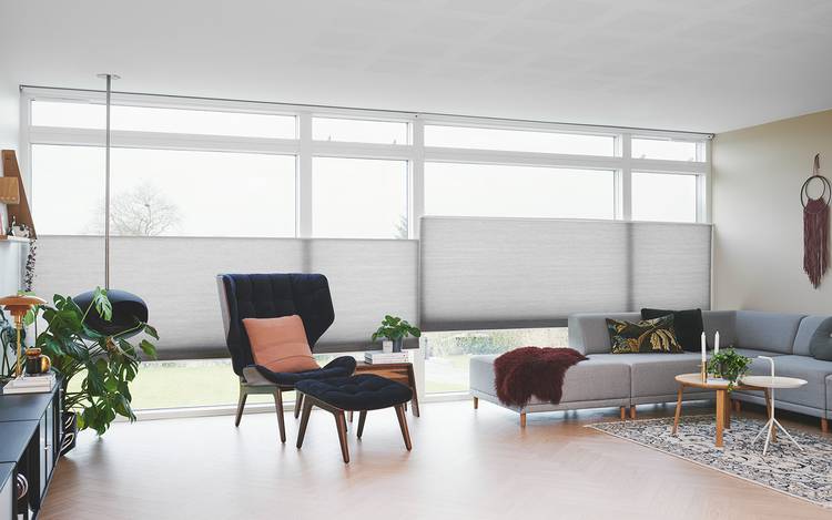 Kraftige Duette® gardiner i dempet grå i stuevinduene til et intelligent hjem